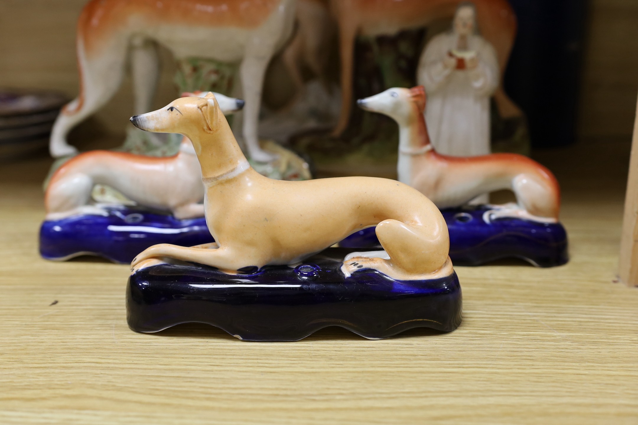 A Staffordshire pottery figure of John Wesley, six Staffordshire pottery models of hounds, and a white bisque group of two hounds on a cushion, tallest 29cm, (8)